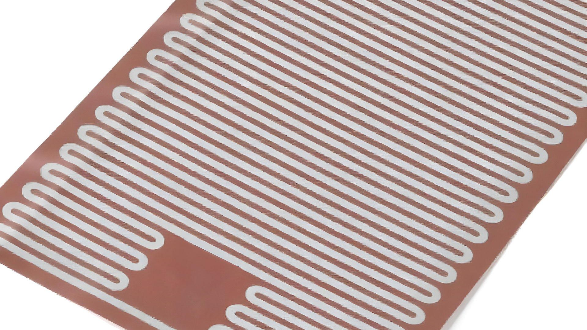 A close-up of a flexible foil heater, the resistance track laid in rows across a red silicone sheet.