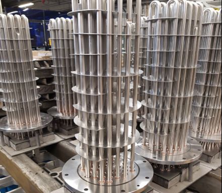 Flanged immersion heater bundles standing in a workshop before assembly.