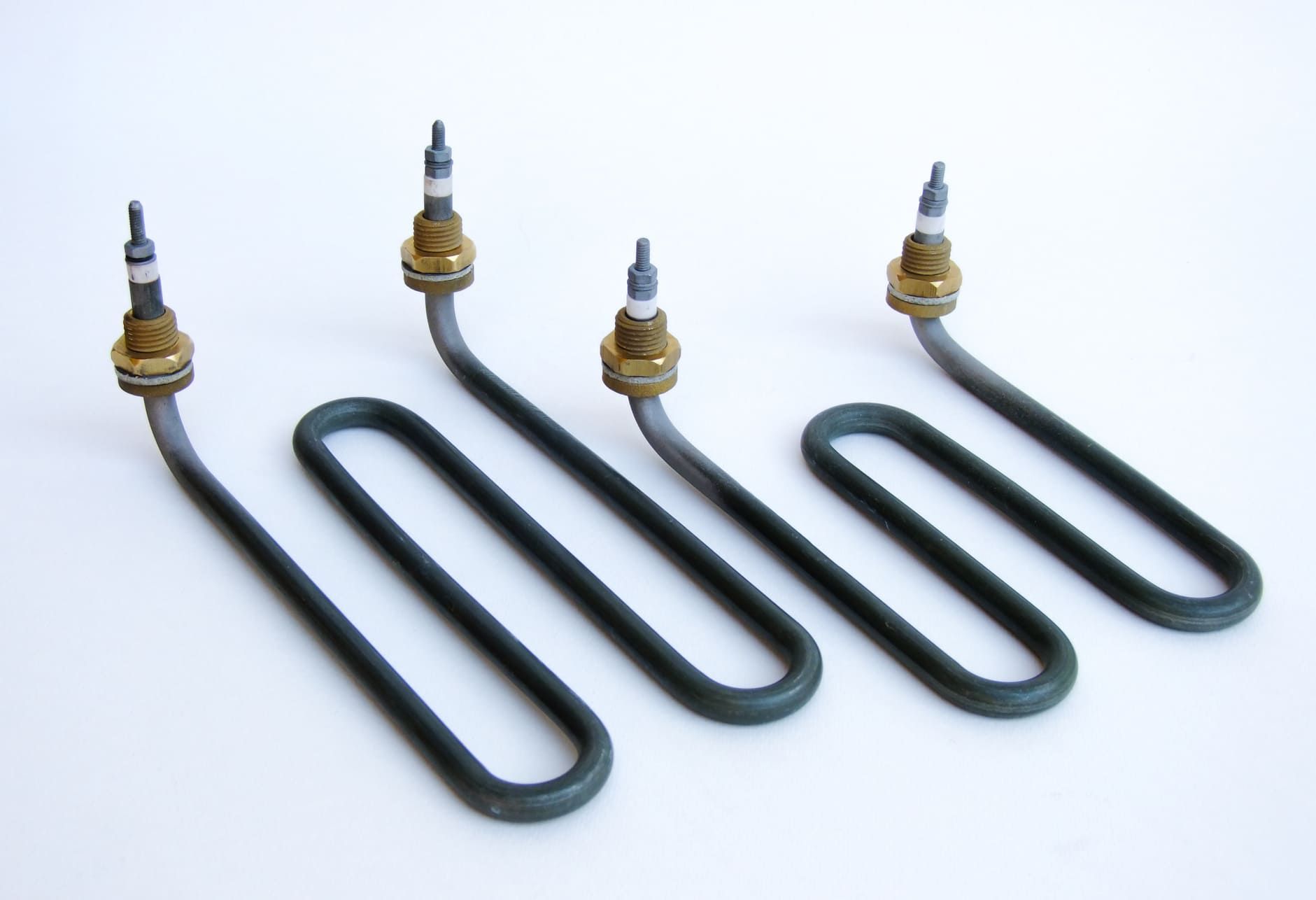 Four samovar elements, each a hairpin tube on a brass boss with a threaded terminal.